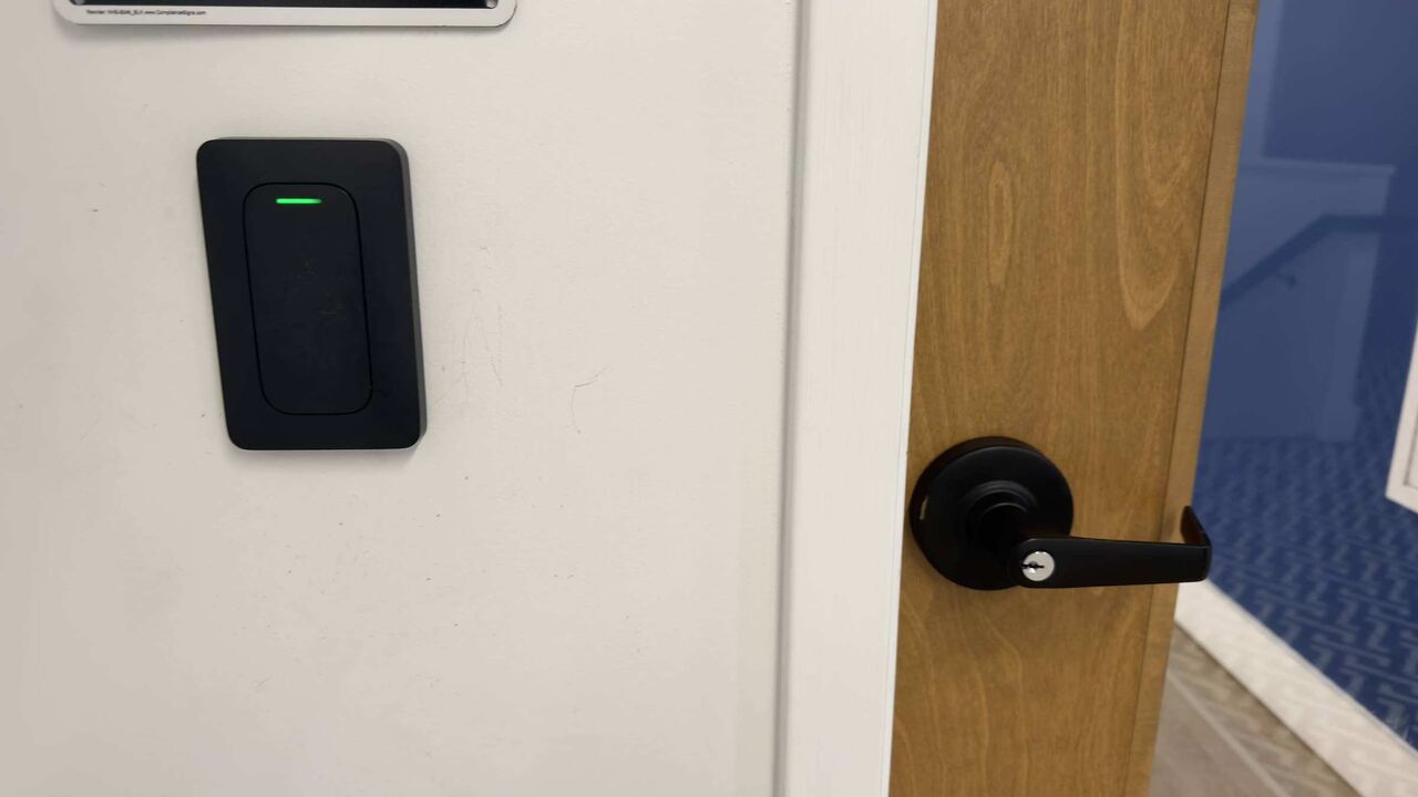 A Verkada card reader beside the suite door, status light green